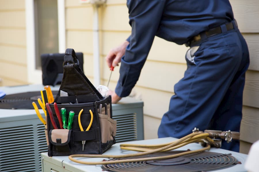 air conditioner technician servicing an outdoor unit