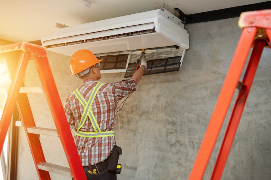 an hvac technician servicing an AC unit