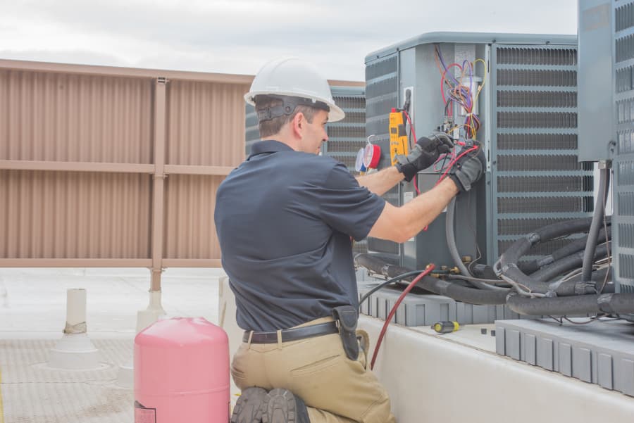 HVAC tech inspecting condenser 