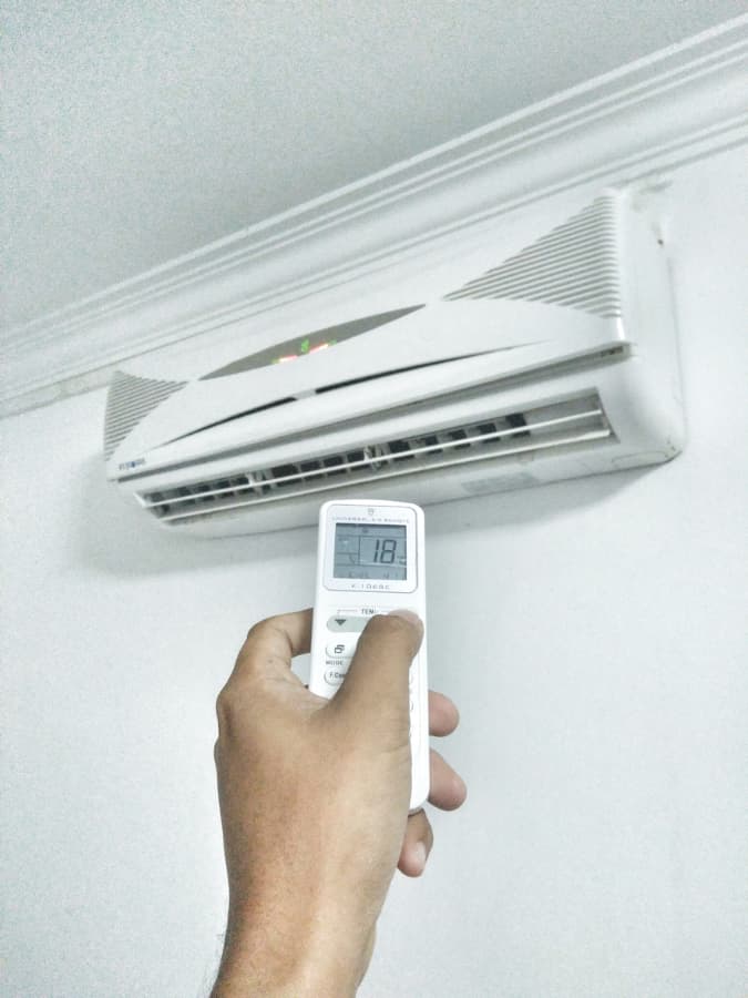 person pointing a remote toward a/c unit