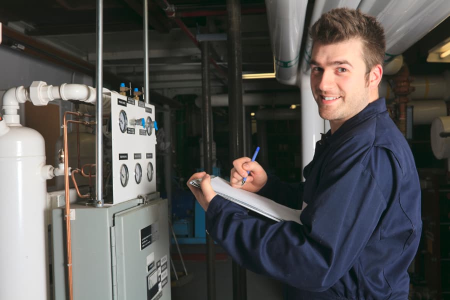 Repair worker writing on clipboard in boiler room